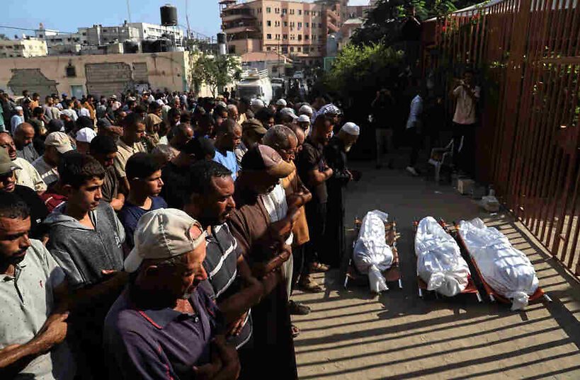 Mourners pray over the bodies of three Palestinians
